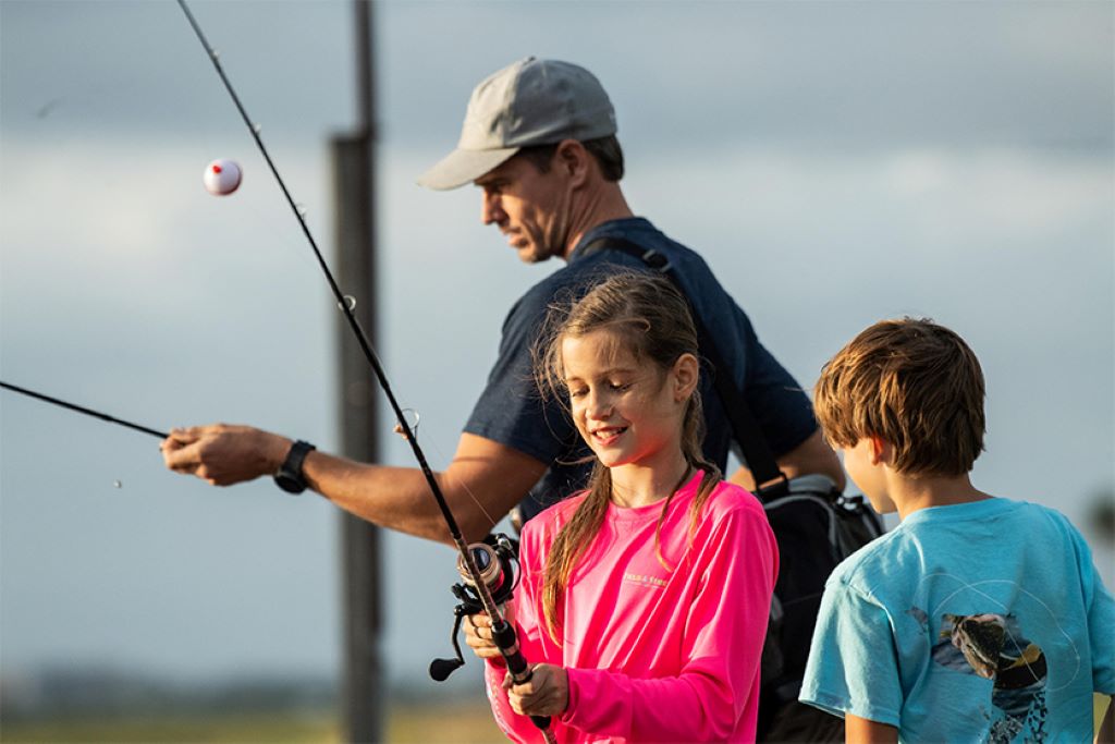 Parent helping child cast a beginner-friendly fishing pole outdoors